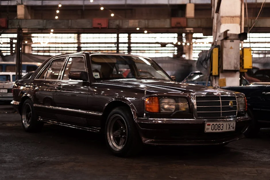 A classic black vintage car parked indoors in an industrial workshop setting with soft lighting. - best affordable project cars for beginners