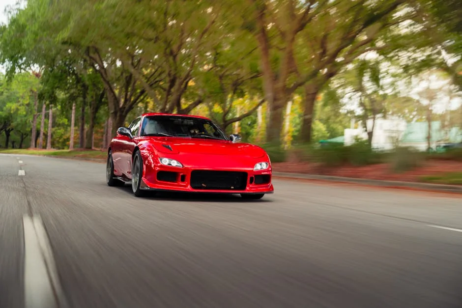 A sleek red sports car in motion on a picturesque, tree-lined road. - best coilovers for daily driving