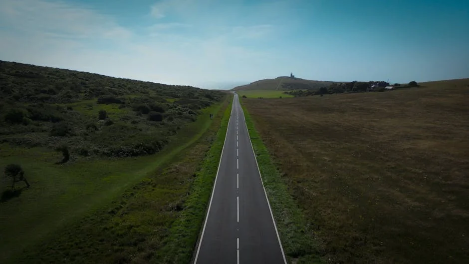 A scenic road leading through the lush countryside of Eastbourne, England on a clear summer day. - best driving roads in the united kingdom