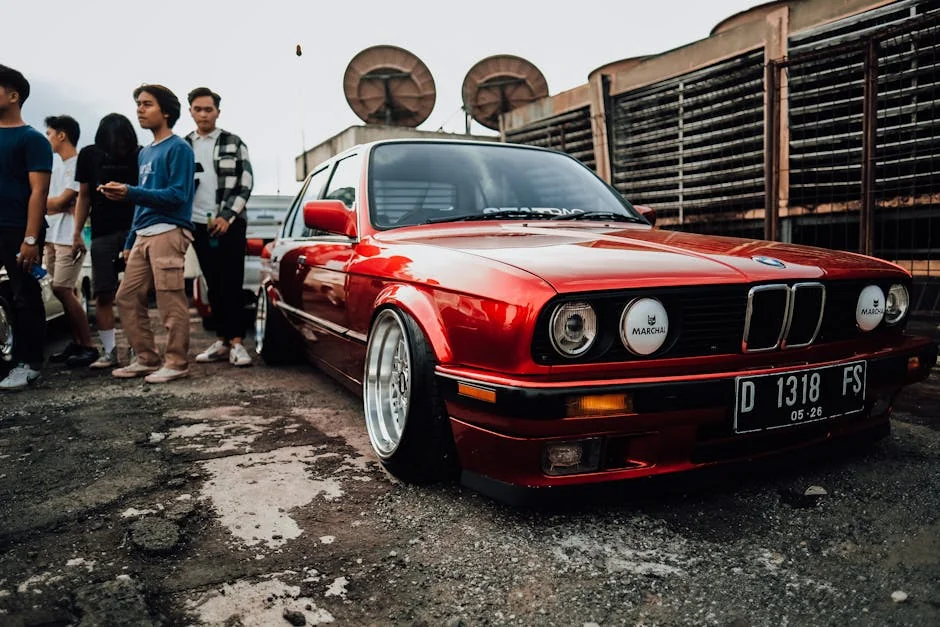 Classic red car displayed at a vibrant automotive meet with enthusiasts. - best first cars for car enthusiasts