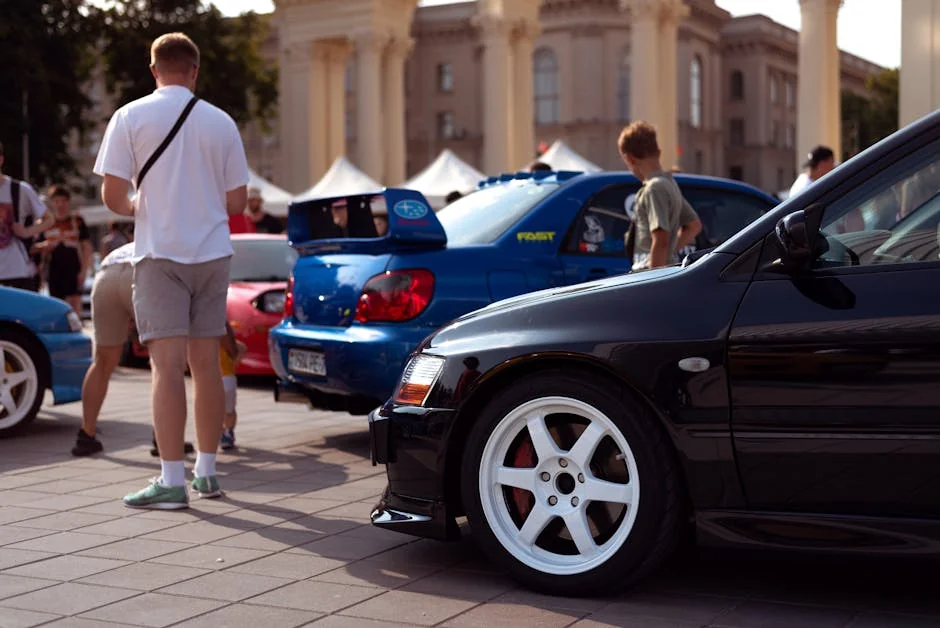 Dynamic urban scene featuring Mitsubishi Lancer and Subaru Impreza in a car show, attracting a diverse crowd. - best first cars for car enthusiasts