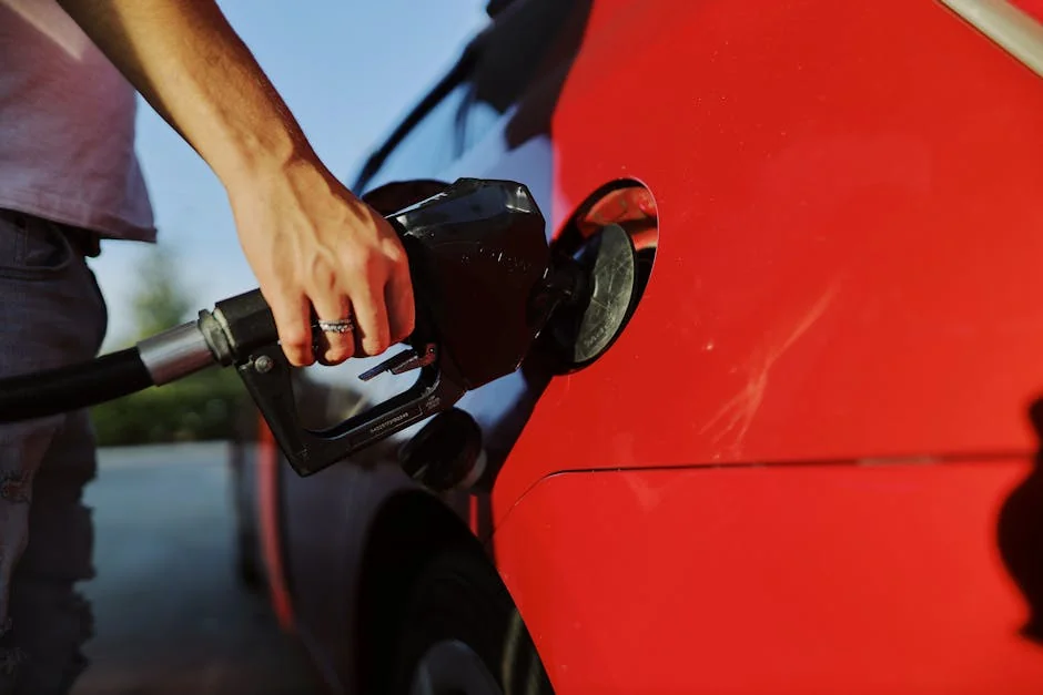 Close-up of a person refueling a red car at an outdoor gas station during the day. - best fuel efficient cars for long commutes