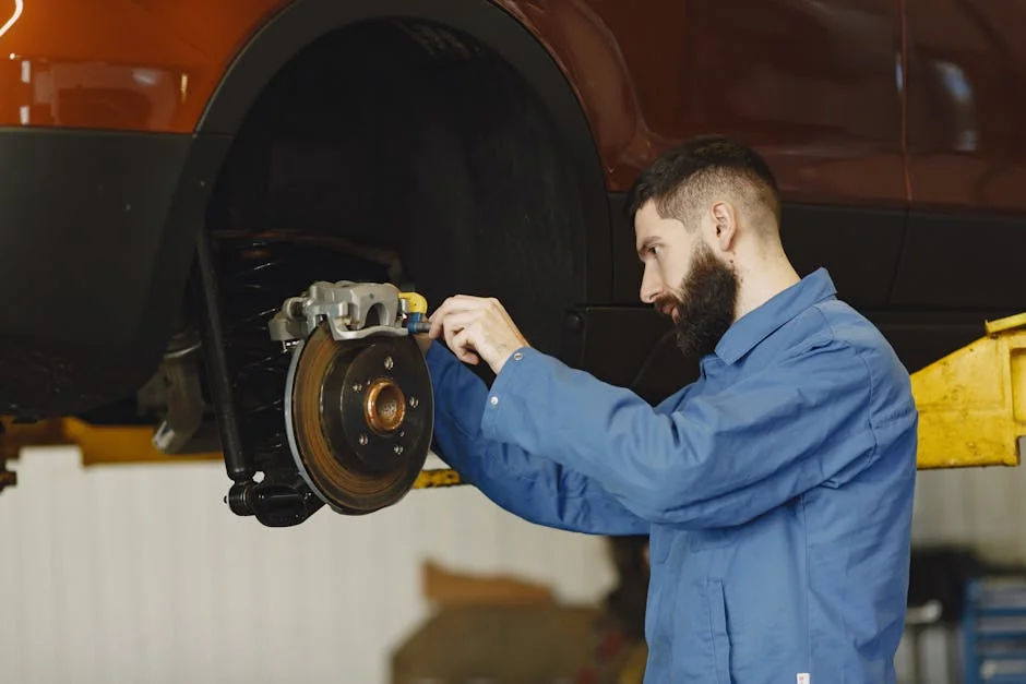 Mechanic in blue uniform performing brake repair on car in modern garage. - brake pad replacement cost guide