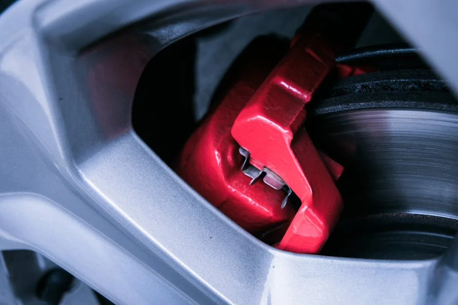 Detailed photo of a red automotive brake caliper and disc brake in focus. - brake pad replacement cost guide