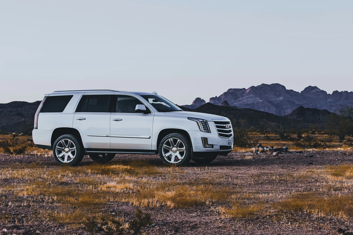 Pearl white Cadillac Escalade at Campsite in the Arizona Desert with mountains in the background. - most reliable used luxury suvs