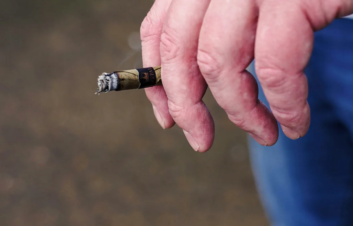 a man holding a cigarette in his hand - symptoms of a bad spark plug